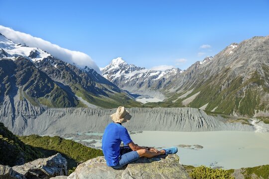 Hiker sitting on a rock, view of Hooker Valley with Mueller Lake, Hooker Lake and Mount Cook, Sealy Tarns Track, Hooker Valley, Mount Cook National Park, Southern Alps, Canterbury, South Island, New Zealand