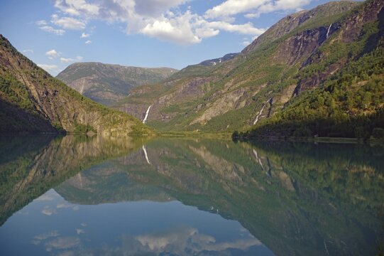 Mountains and waterfall reflected in the calm waters of a lake, Idyll, Skjolden, Western Norway, Norway