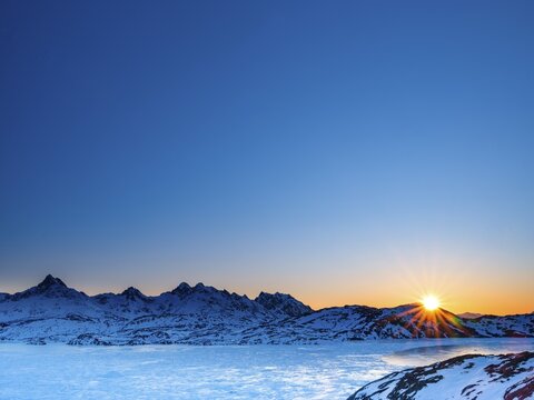 Sunrise over snowy mountains above the frozen Kong Oscar Fjord, Tasiilaq, Ammassalik Island, Kommuneqarfik Sermersooq, East Greenland, Greenland