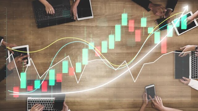 A collaborative business meeting showcases hands using tablets and laptops on a wooden table, analyzing financial trends and data for strategic decision-making. Copula