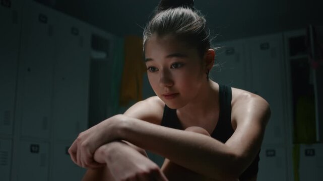 Tired Teenage Sitting Alone on Bench, Burying Head in Arms, Hugging Knees. Raw Emotion of Physical Exhaustion, Elite Sport Burnout, Mental Breakdown of Young Competitor after Intense Training Session.