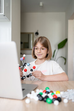 STEM education. The girl is focused on the molecular model. Science education at hone. Child studying chemistry online. 