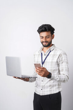 Young business professional using a smartphone while holding a laptop on plain white background