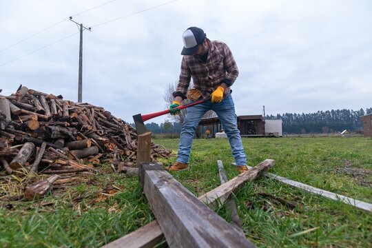Full length low angle view of a strong latino man preparing to split logs on a cloudy day