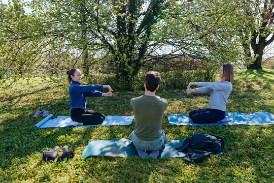 Friends Practicing Outdoor Stretching on Yoga Mats in a Park