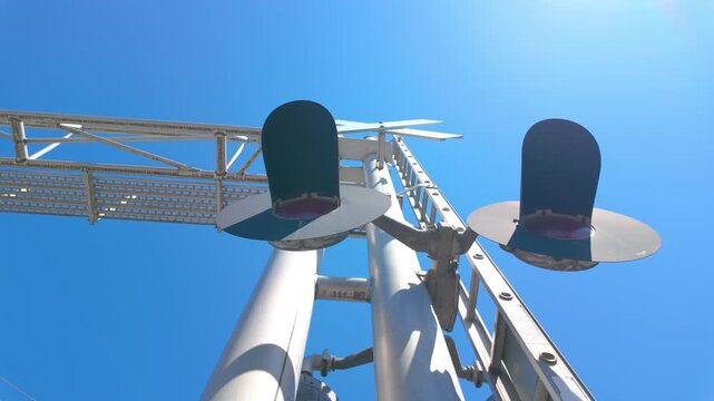 Railway crossing signal lights on steel mast under blue sky