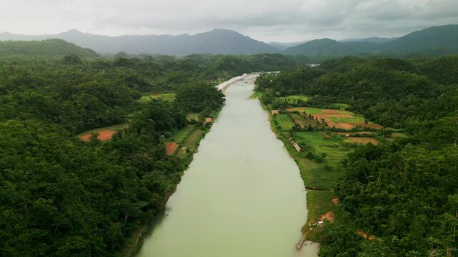 Panoramic aerial view of wide river framed by lush forest, farmlands, and mountain ranges - Pajo, Virac, Catanduanes, Philippines