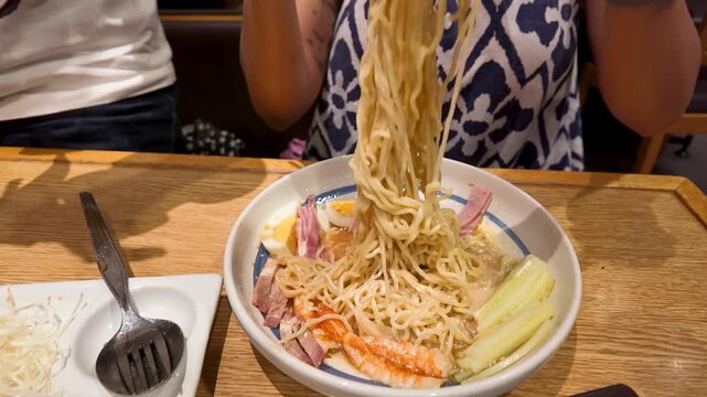 Woman Eating Asian Ramen Noodles with Chopsticks in Restaurant