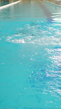 Athletic woman swimming the butterfly stroke in a competition swimming pool during a training session, showcasing her strength, technique, and dedication to the sport in crystal clear blue water