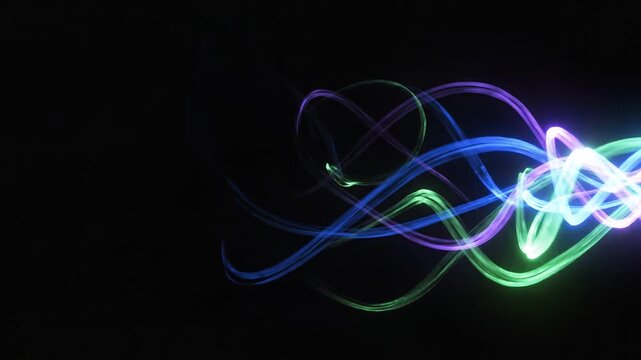 Vibrant blue, green, and purple light trails swirl on a black abstract background, creating a dynamic energy flow.