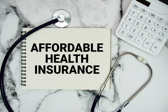 Affordable Health Insurance text written on notepad with stethoscope and  calculator on marble background