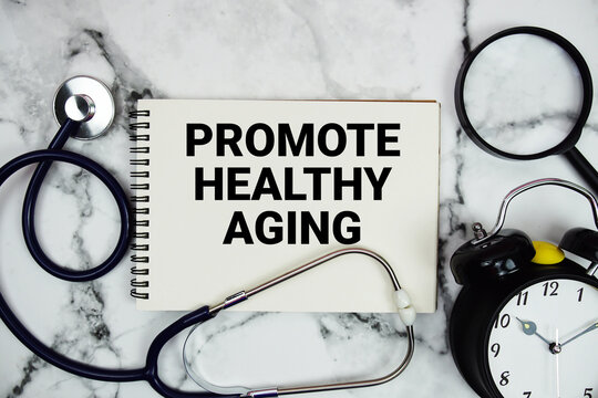 Promote Healthy Aging text written on notepad with stethoscope and magnifying glass on marble background