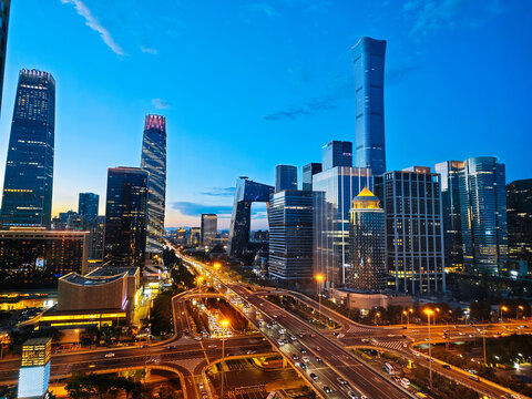 Elevated city view of Beijing CBD skyline featuring China Zun tower and Guomao (China World Trade Center, China World, China World Towers, CWTC) overpass with traffic light trails at twilight