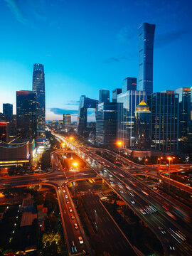 Elevated city view of Beijing CBD skyline featuring China Zun tower and Guomao (China World Trade Center, China World, China World Towers, CWTC) overpass with traffic light trails at twilight