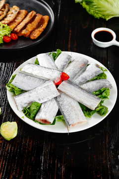 Fresh Raw Striped Bass Sashimi Fillets with Lettuce and Soy Sauce on Dark Wood Table