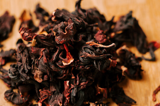 Dried hibiscus flowers piled on a wooden surface for herbal tea preparation during the morning time