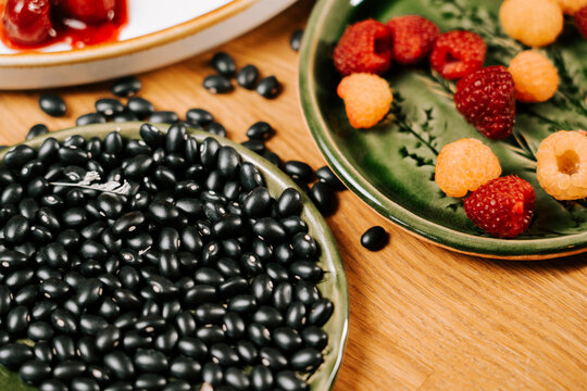 Black beans and fresh raspberries served on decorative green plates during a morning snack at home