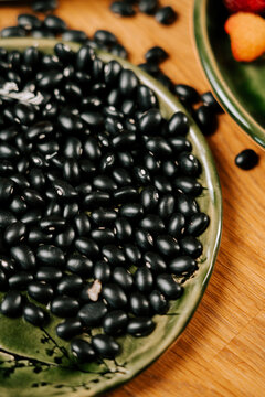 Black beans served on a green ceramic plate placed on a wooden table surface for a healthy meal