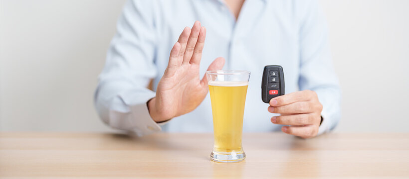 Responsible man reject a drink before driving for road safety, Man making stop hand gesture to refuse a glass of Beer and car remote. Avoid drink and drive, Drunk Driving Law concept
