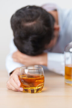 Stressed man drinking whiskey alone with problem. Exhausted drunk man looking stressed and sleepy. Alcohol addiction, Alcoholism, emotional distress and mental health concept