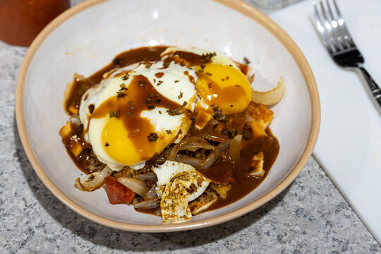 Creative homemade loco moco made with pepperoni pizza fried rice, saut&eacute;ed onions, sunny-side-up eggs, brown gravy, and dried herbs in a white bowl.