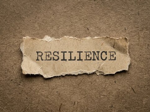 Resilience Concept, torn paper with typed word showing strength and endurance through adversity on a textured background