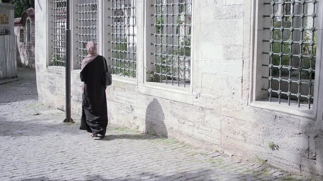 Woman walking by stone wall and windows in a quiet area