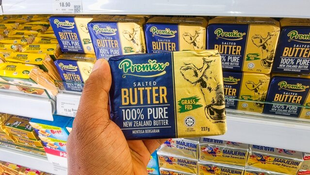 Malaysia Kuala Terengganu, 20 July 2026 : Hands holding butter brand promex and golden churn in the supermarket. Close up of Golden Churn brand of butter for sale