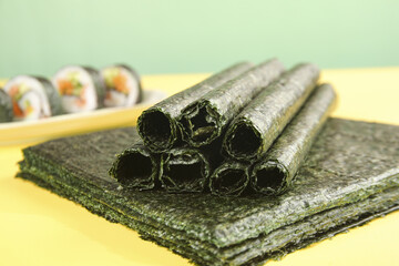 Nori Seaweed Sheets and Rolls for Sushi Making with Traditional Japanese Food in Background © DinhThi
