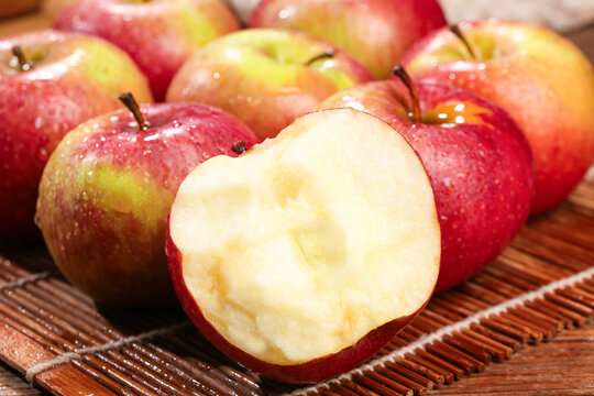 Fresh red apples with a bitten apple on bamboo mat