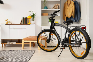 Modern gray bicycle with yellow rims parked in a bright, minimalist living room with white furniture © Pixel-Shot
