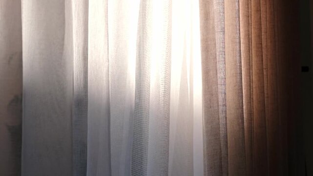Light filters through sheer fabric curtains as the wind gently sways