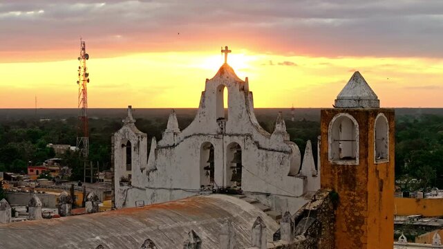 Aerial view of the San Antonio convent at golden hour in Izamal, Yucatan, Mexico, warm light silhouetting its towers above the colonial town.