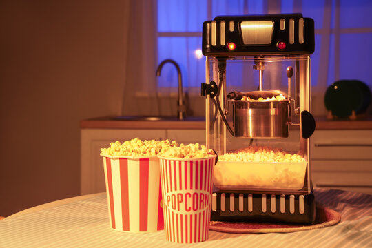 Modern popcorn machine on table in kitchen at night