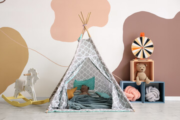 Cute toys in drawers with baby play tent and rocking horse near color wall © Pixel-Shot