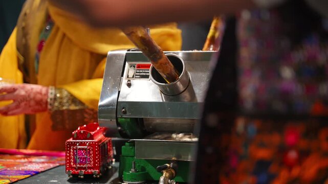 Fresh sugarcane juice being extracted with a commercial sugarcane press at a food stall. Close up