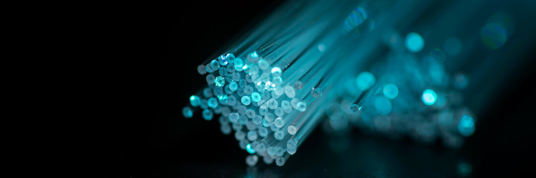 Macro view of glowing blue fiber optic cable strands with technology communication internet transmission electronic connectivity bandwidth connection infrastructure