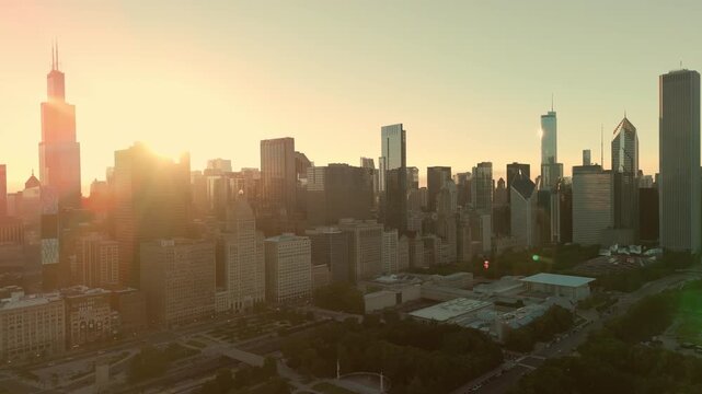 Aerial view of the Chicago skyline at golden hour with the sun rising behind the city's iconic skyscrapers. Cinematic drone footage