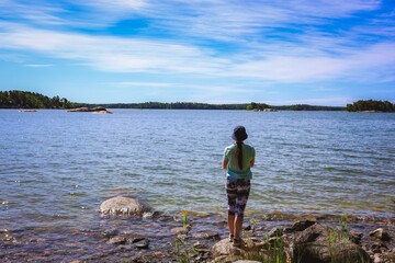 Fototapeta premium A woman catches a spinning fish while standing on a riverbank Stock Photo