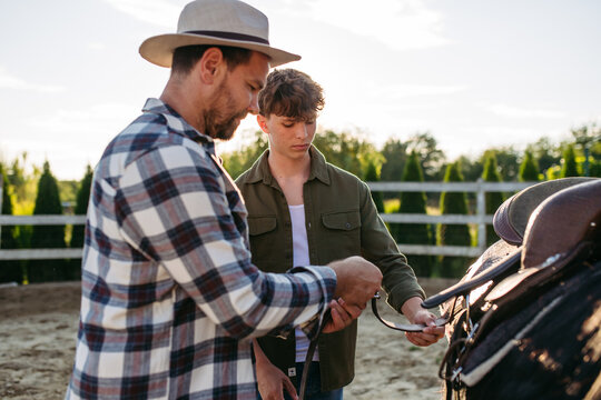 ather and son preparing horse for riding.