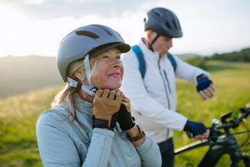 Older bikers taking break during bike ride and checking their performance on smartwatch. © Halfpoint