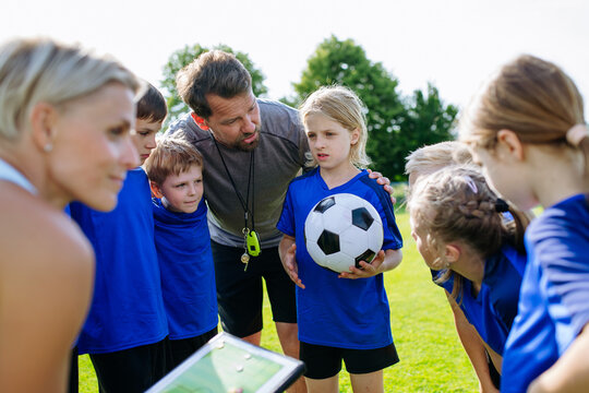 Youth soccer team talking with coaches about game strategy during practice.