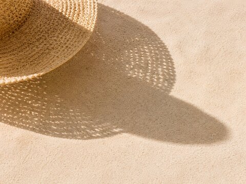 Straw hat shadow on pale summer sand