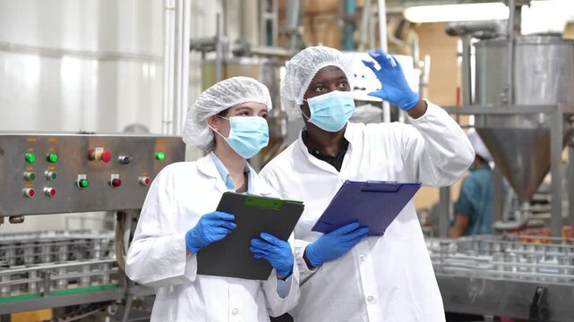 Food safety inspectors reviewing canned fish production while discussing quality standards inside seafood processing factory. Quality control, manufacturing inspection, hygiene compliance.