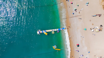 Oludeniz, Turkey. Aerial top down view of Oludeniz Beach with rows of umbrellas, crowded pebble shore, sea waves and pontoon pier in turquoise water, summer.. Aerial View © Video Render