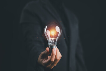 Businesswoman holding glowing light bulb representing innovation, creative idea and business inspiration. Concept of startup success, leadership, technology and strategic thinking. © Goodtime