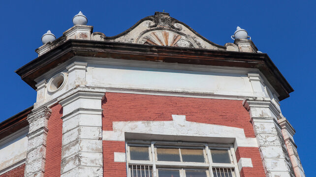 Historic red brick building facade with white ornate architectural pediment