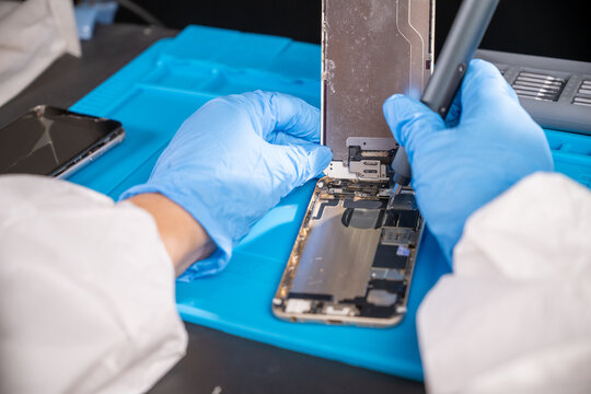 Smartphone technician repairing disassembled mobile phone hardware.