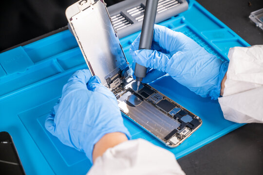 Smartphone technician repairing disassembled mobile phone hardware.