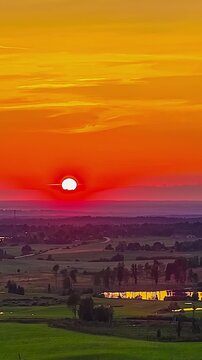 Sunset timelapse over rural landscape with fields, trees, and reflective ponds